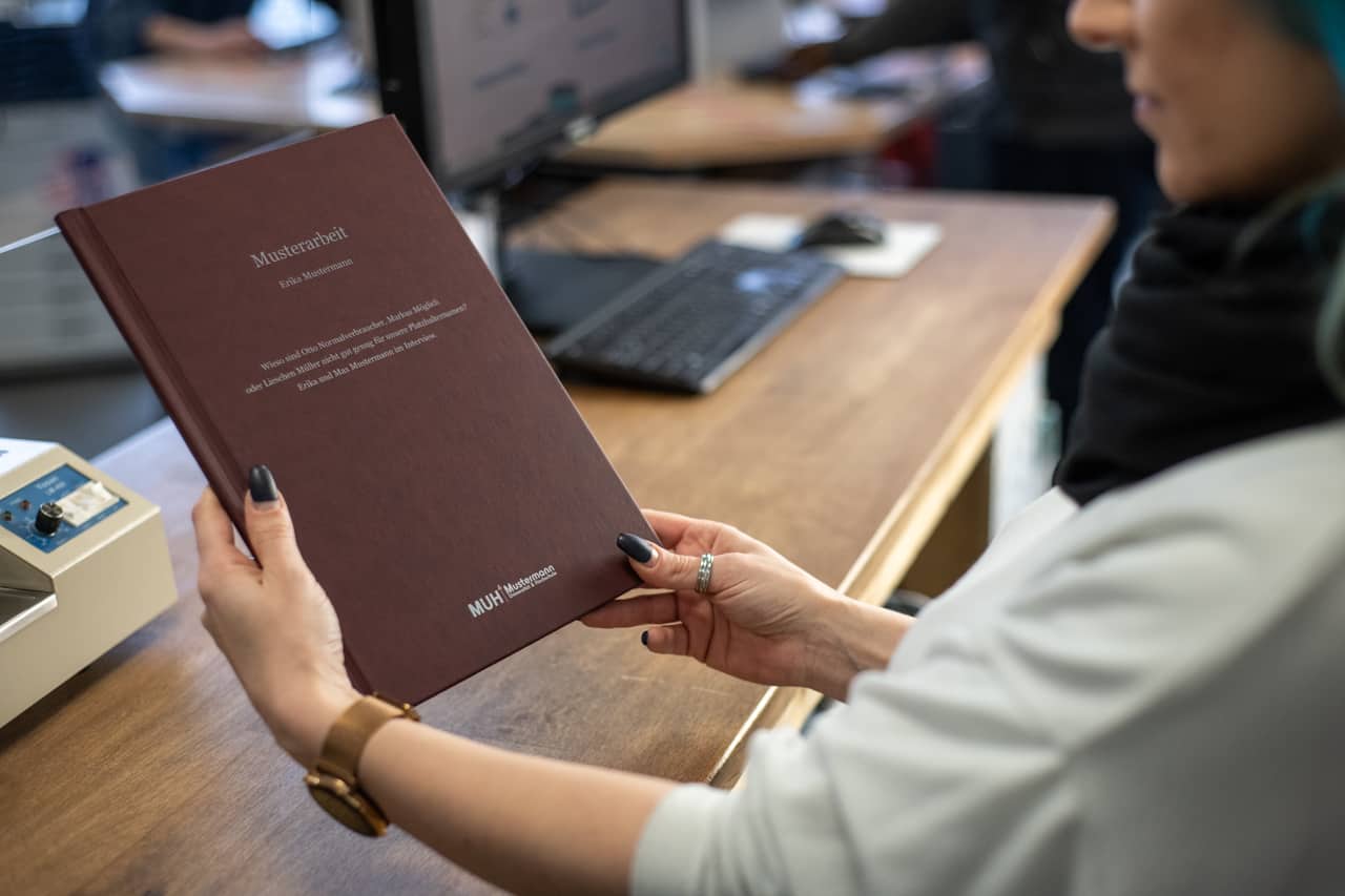 CopyShop_CopyTerra_berlin_Bindung_Hardcover_rote-Mappe_mit-Beschriftung_gebunden_haltend_feste-Bindung_Beispielbild_CopyTerra