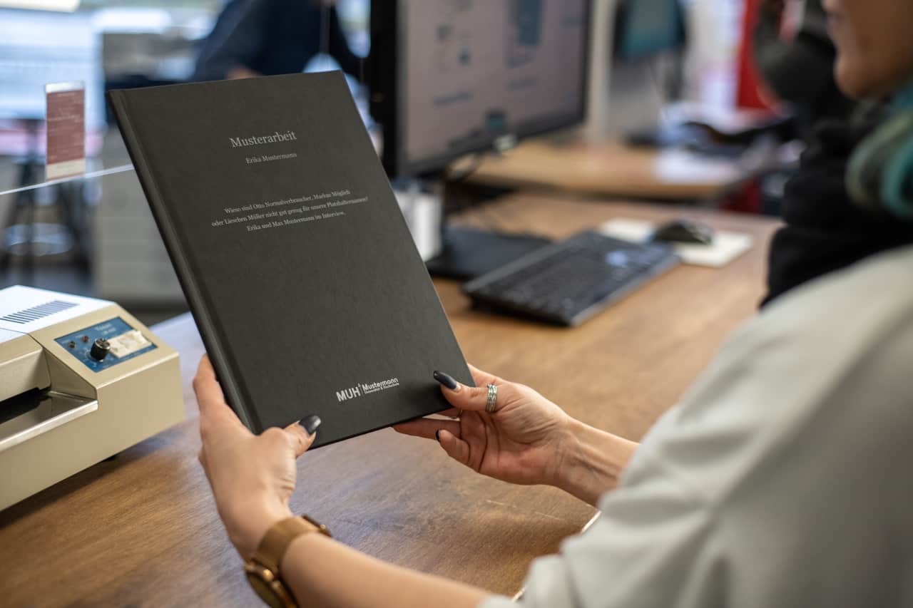 CopyShop_CopyTerra_berlin_Bindung_Hardcover_schwarze-Mappe_mit-Beschriftung_gebunden_haltend_feste-Bindung_Beispielbild_CopyTerra